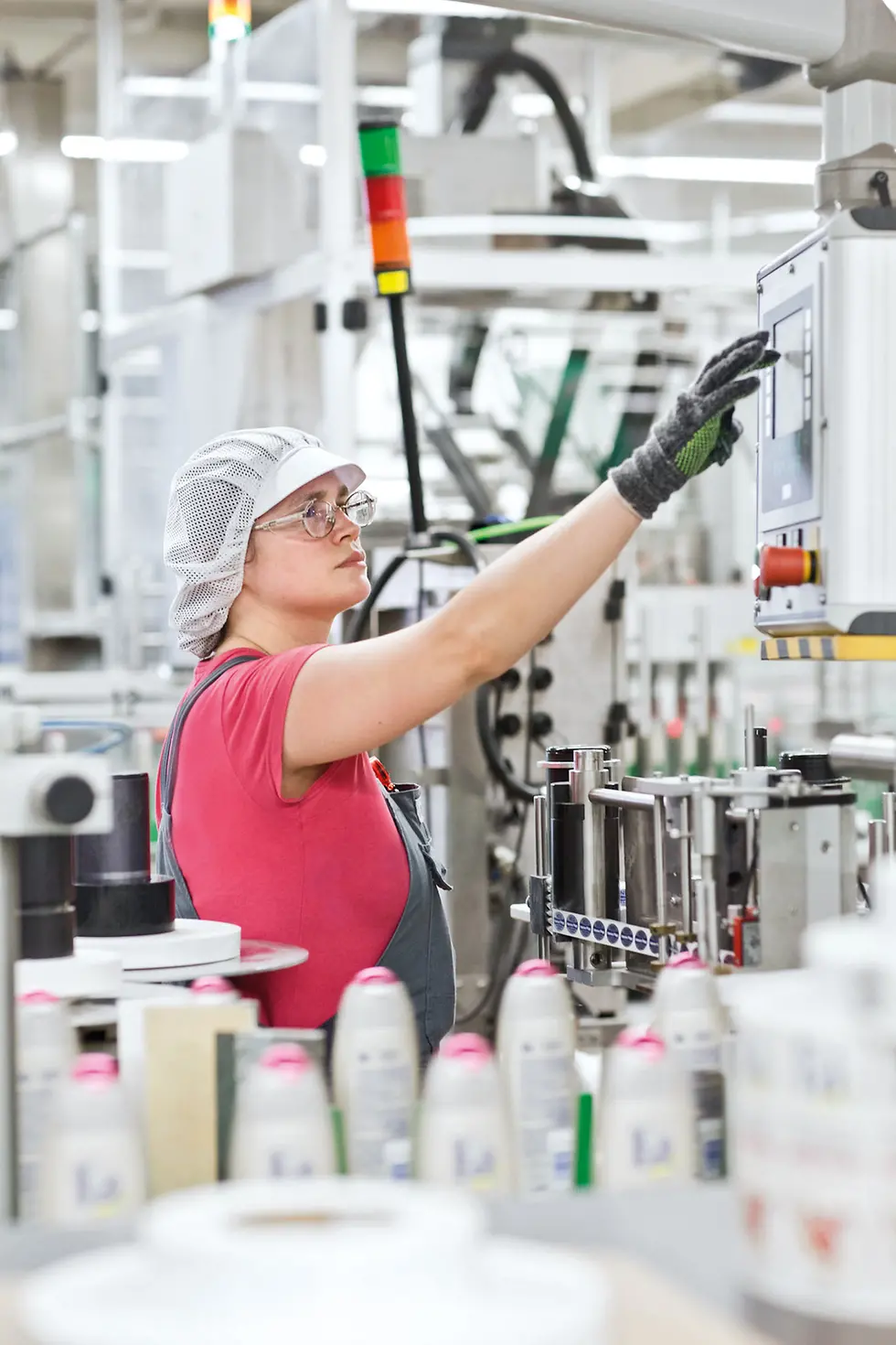 A female employee at the Beauty Care production site operates the touchscreen of a machine. 